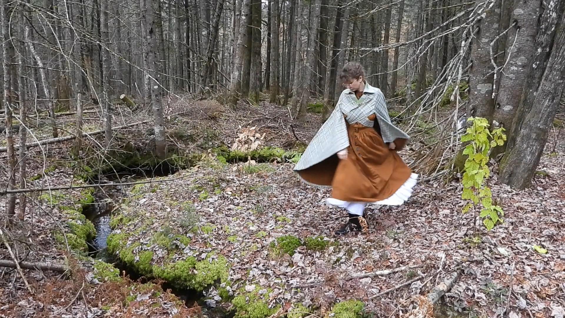Sarah Labarre posant de plain-pied en robe de flanelle ocre et cape en laine édouardienne.